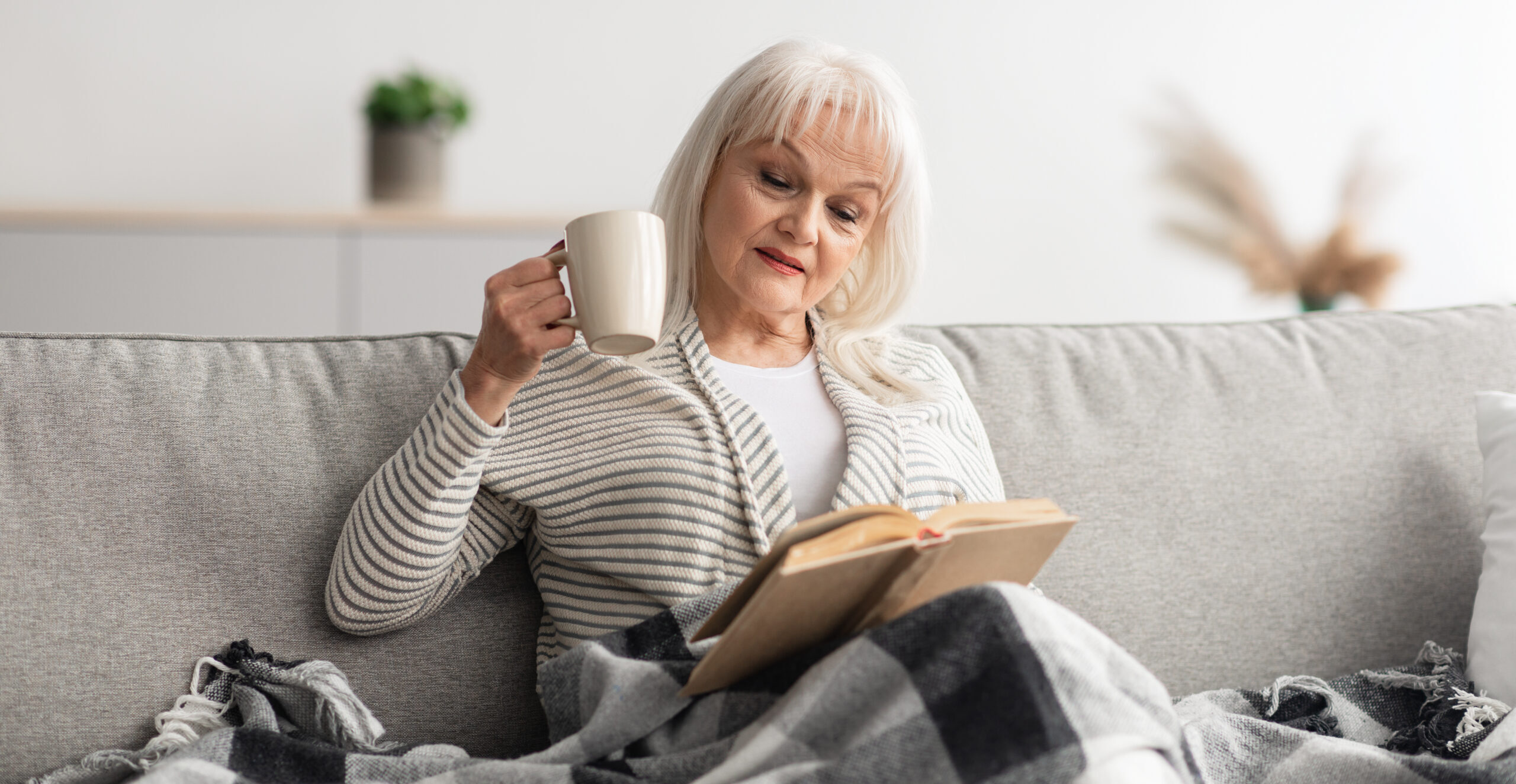 Woman drinking tea and reading on a couch