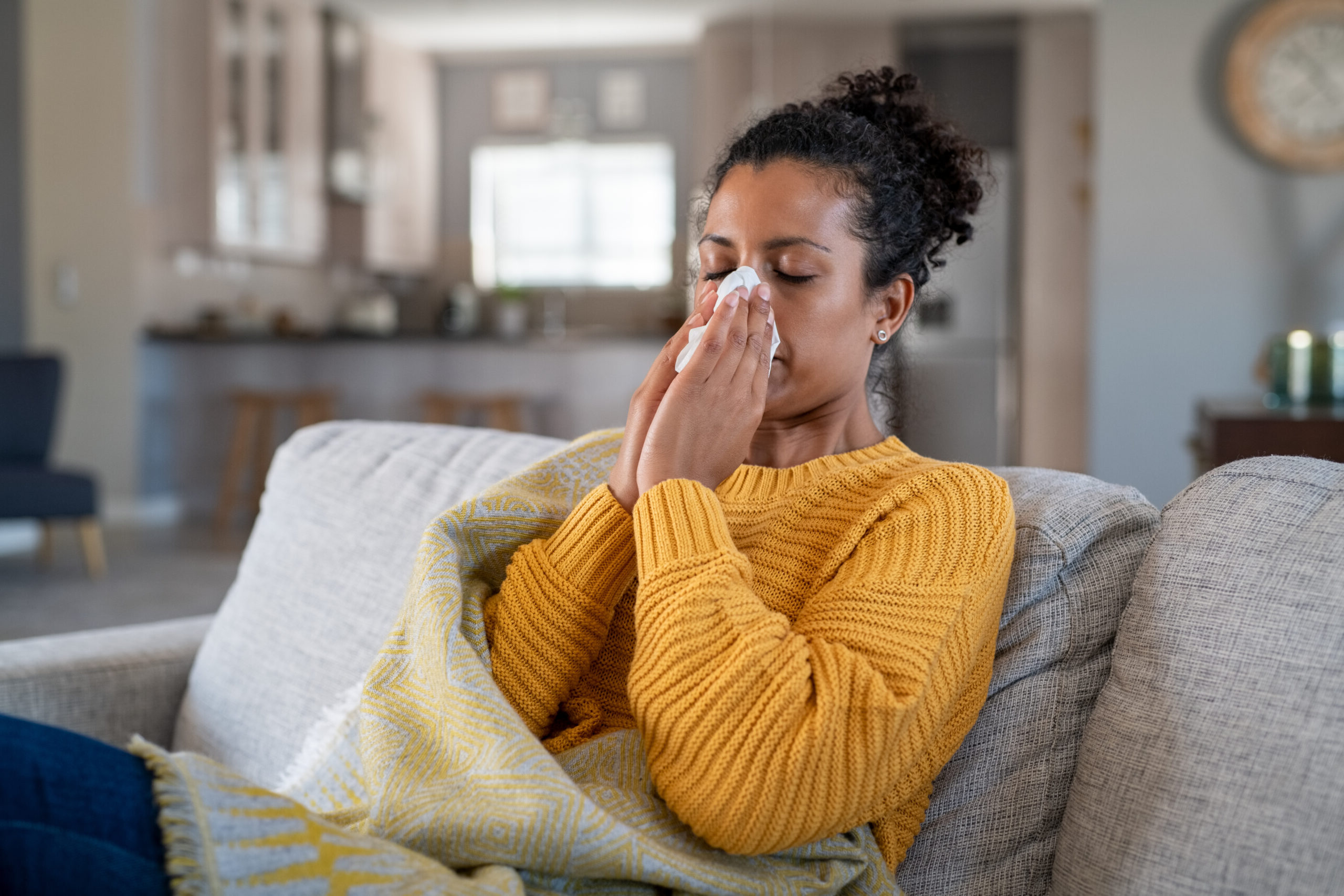 Person on the couch blowing her nose